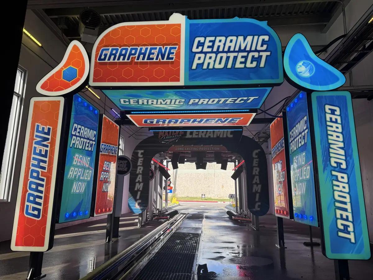 Car wash tunnel entrance with blue and orange Graphene Ceramic Protect signage.