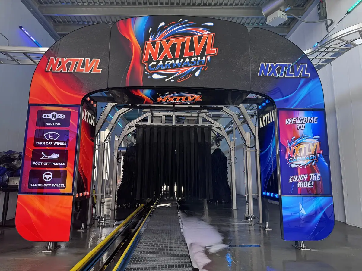 NXTLVL Car Wash entrance archway with red-blue graphics and instructions leading into wash tunnel.