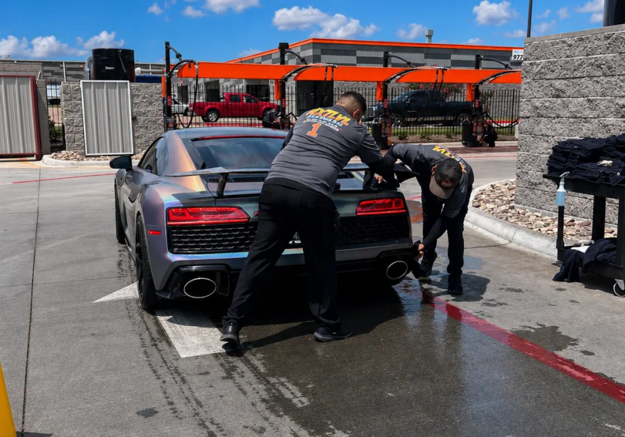 Two NXTLVL team members hand-drying an Audi R8 under the vacuum canopy